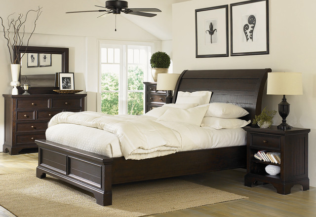 Dark wood bedroom set with white bedding and ceiling fan.