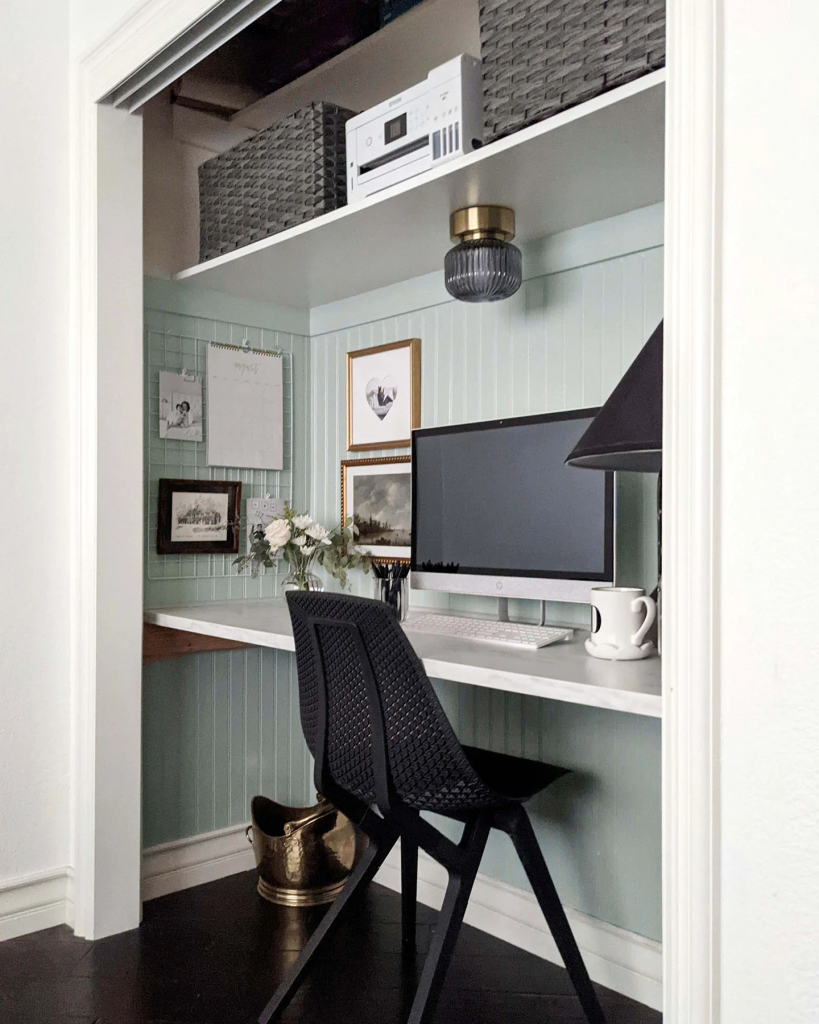 Closet home office with a built-in desk, black chair, and decorative storage baskets.