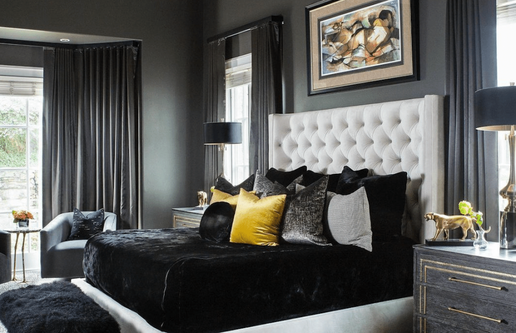Luxurious bedroom with tufted headboard and bold black and yellow pillows.