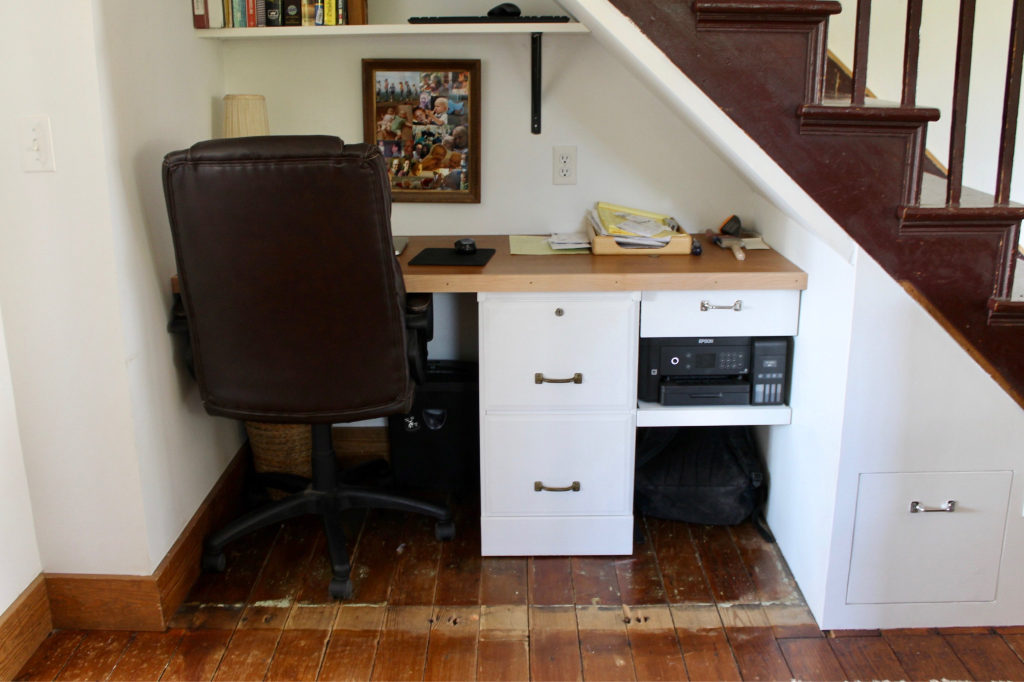 Small office desk under staircase with leather chair and storage drawers