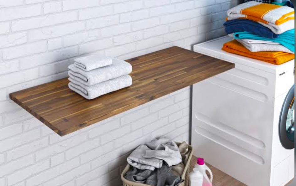 Wooden folding shelf above laundry basket with folded towels