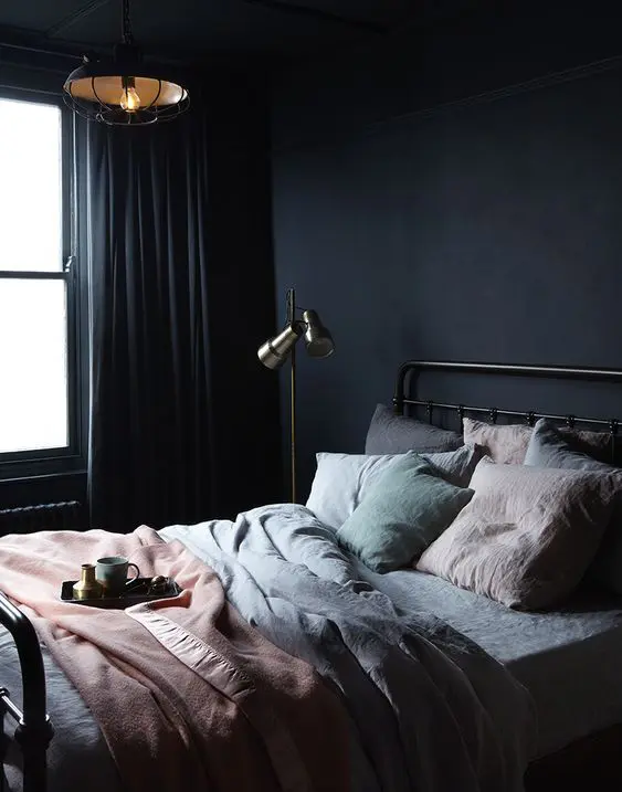 Cozy bedroom with dark walls and soft pastel bedding.