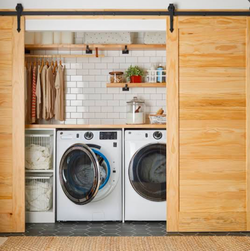 Closet laundry room with sliding barn doors and hanging clothes.
