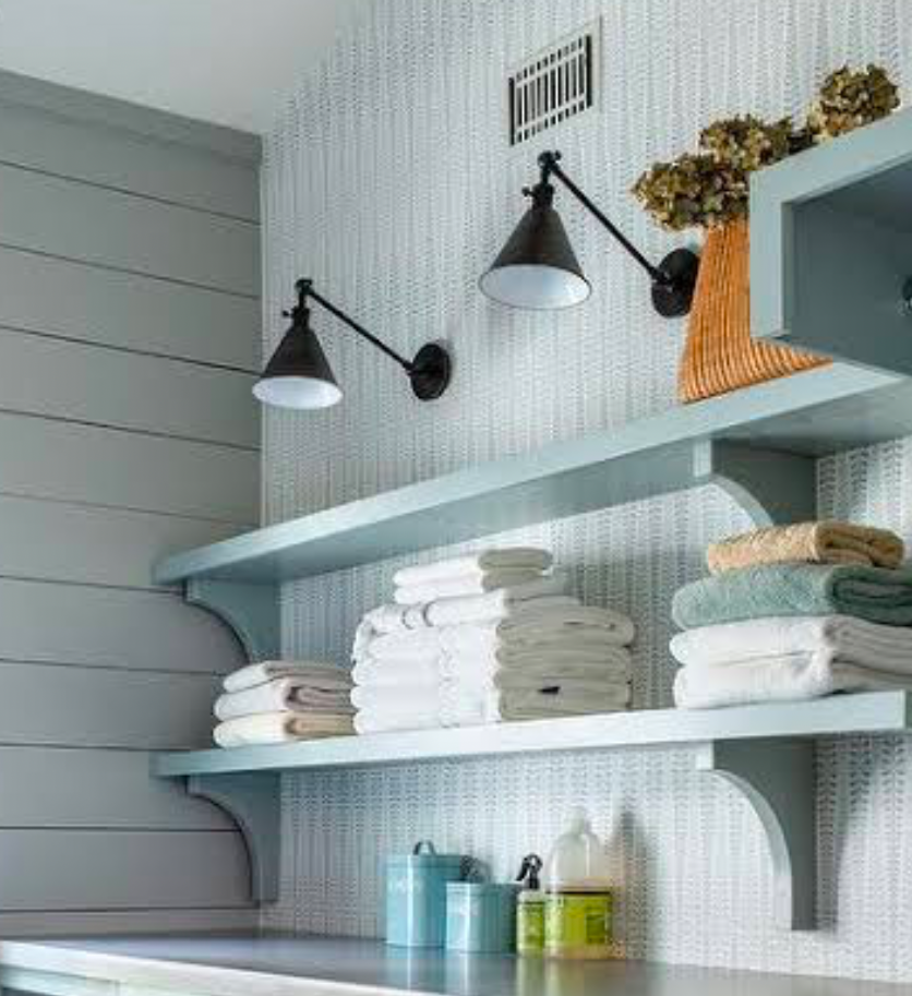 Open shelving in laundry room with stacked white towels and jars