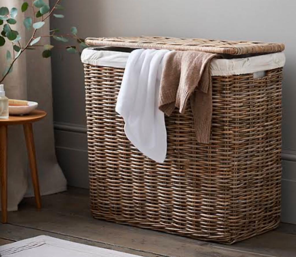 Woven laundry hamper with clothes draped