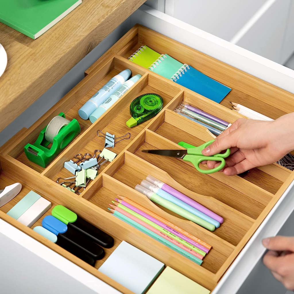 Bamboo drawer organizer holding various colorful stationery items neatly.