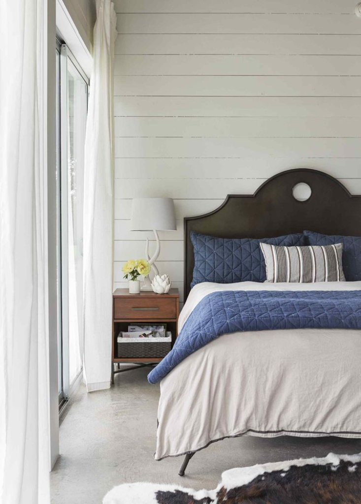 Cozy bedroom with blue quilted bedding and wooden nightstand.