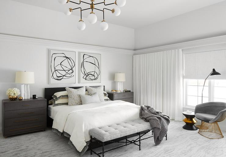Bright bedroom with white curtains, gray bed, and modern chandelier.