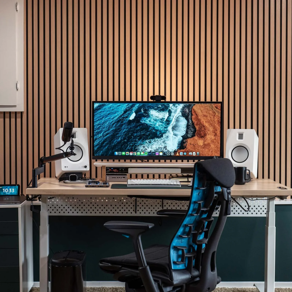 Modern ergonomic workspace with large monitor and studio speakers.