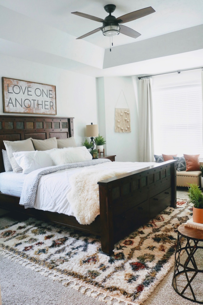 Rustic bedroom with dark wood bed frame and patterned rug.