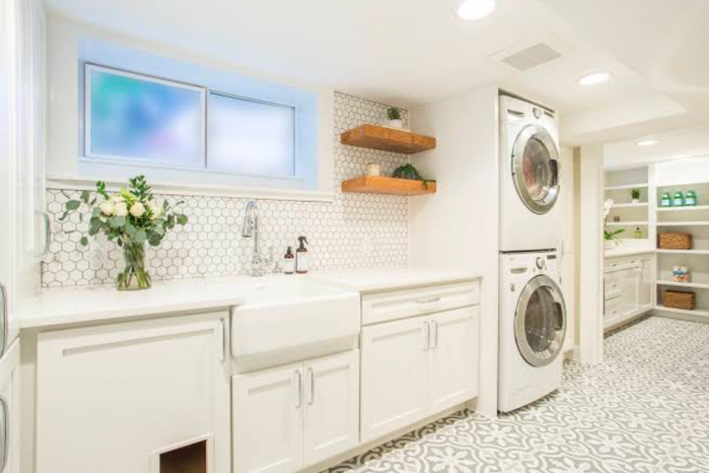 Bright laundry room with white cabinets and stacked washer and dryer.