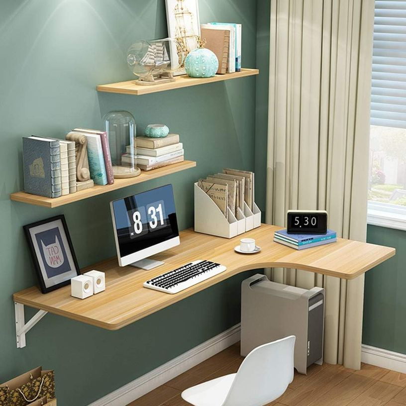 Corner home office with floating shelves, books, and an organized computer desk.