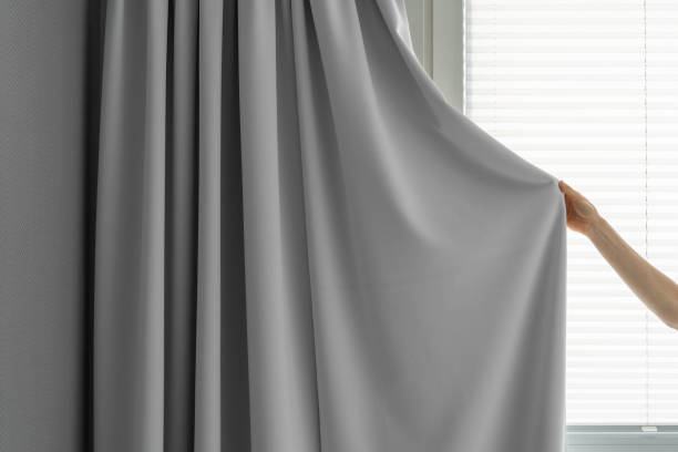 Hand holding elegant grey bedroom curtains.