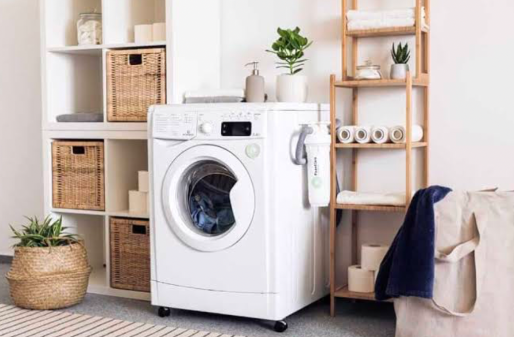 Laundry room with front-loading washer, woven baskets, and wooden shelving.