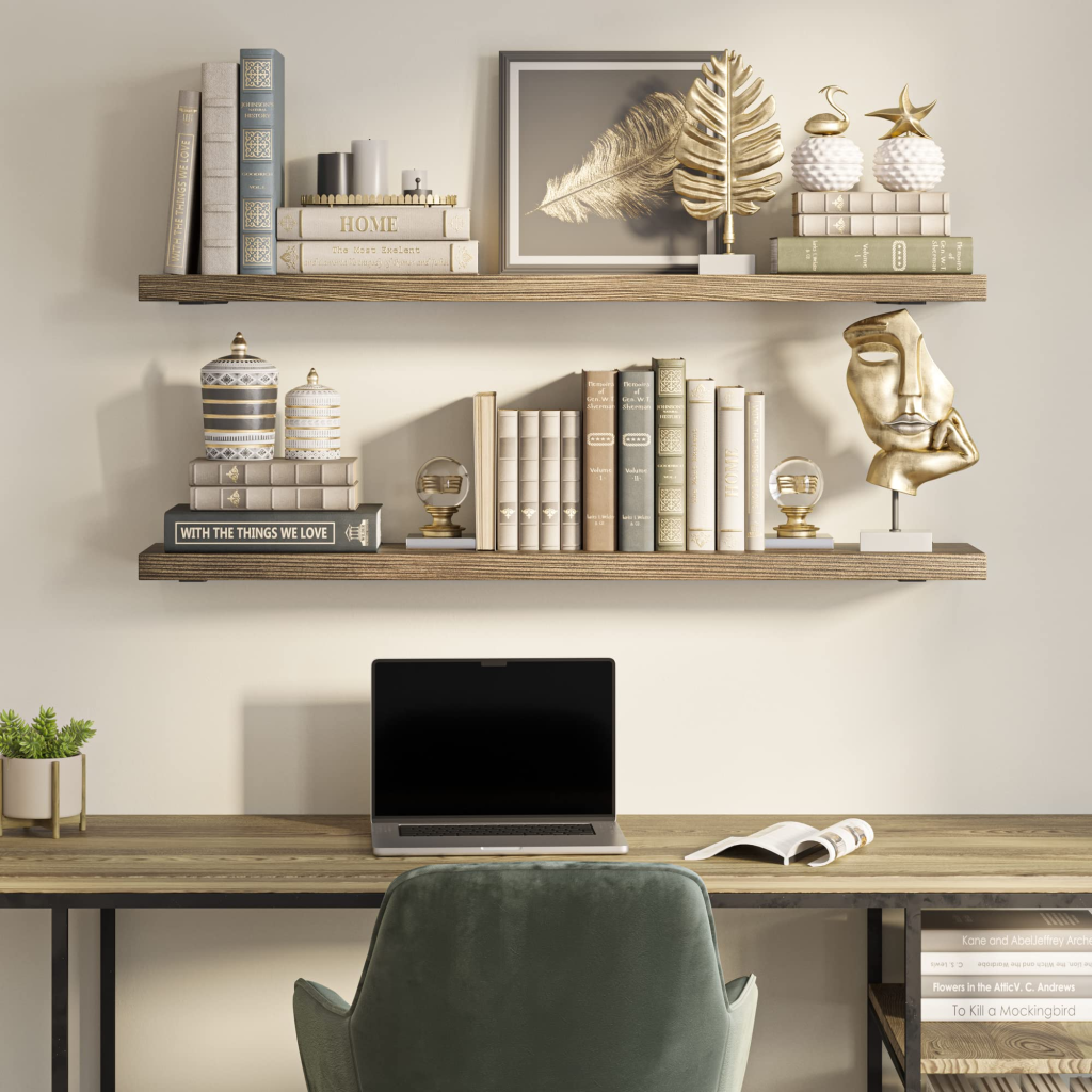 Home office desk with floating wooden shelves, books, and gold decorative sculptures against a beige wall.