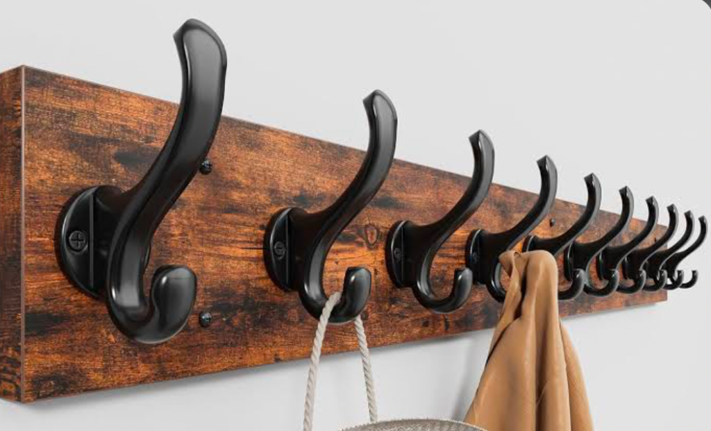 Row of black coat hooks on a rustic wooden board.