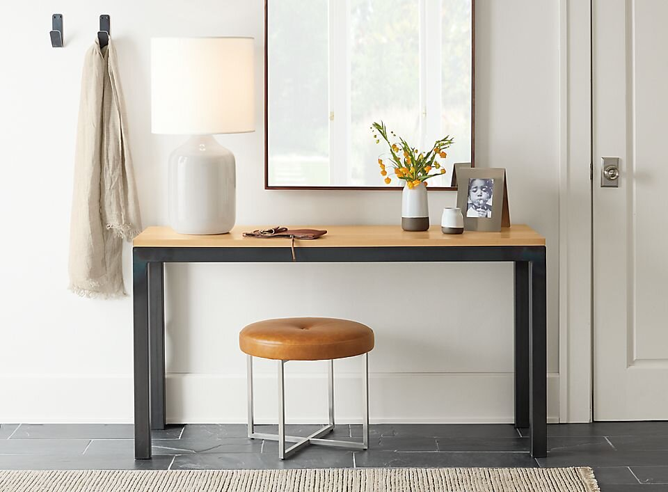 Entryway-style workspace with a narrow table, lamp, and stool under a large mirror.