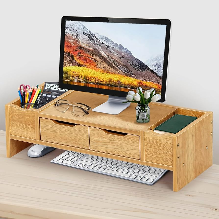 Wooden monitor stand with drawers and office supplies.
