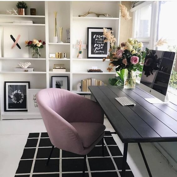 Modern office with black desk and pink chair.