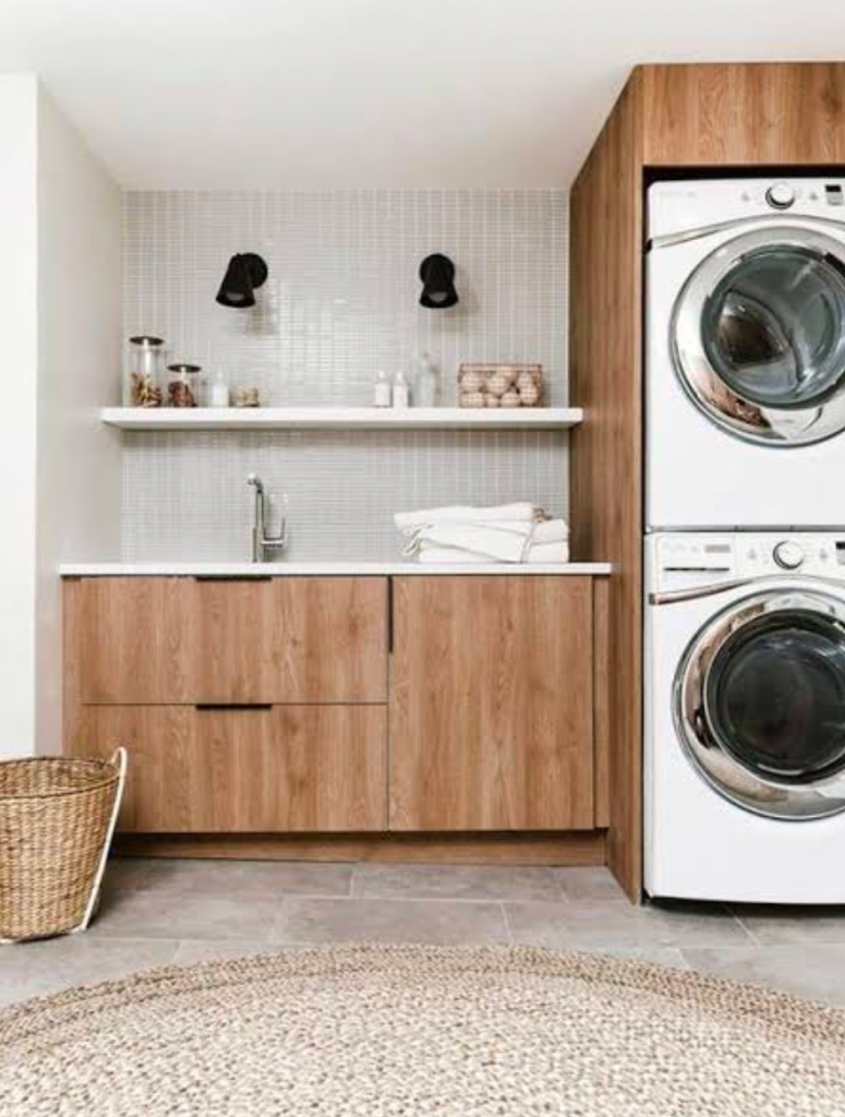Modern laundry room with wood cabinets and stacked appliances.