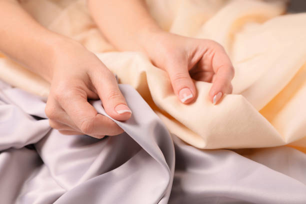 Hands touching smooth silk and cotton fabrics