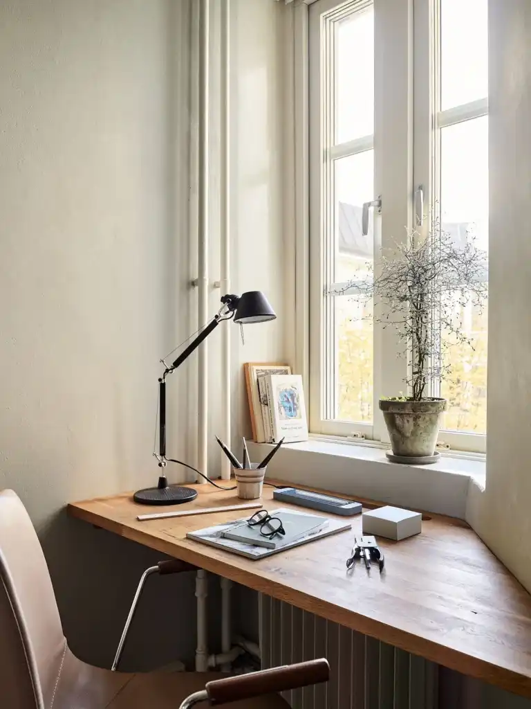 Corner workspace with wooden countertop and black task lamp by a window.