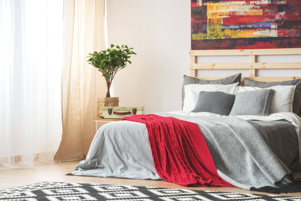 Bedroom with red throw blanket and stylish fabric layers