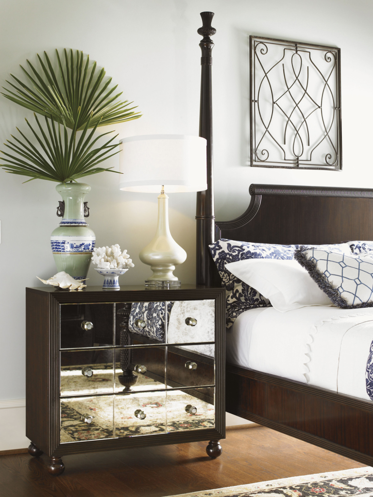 Luxurious bedroom with mirrored nightstand and palm decor.
