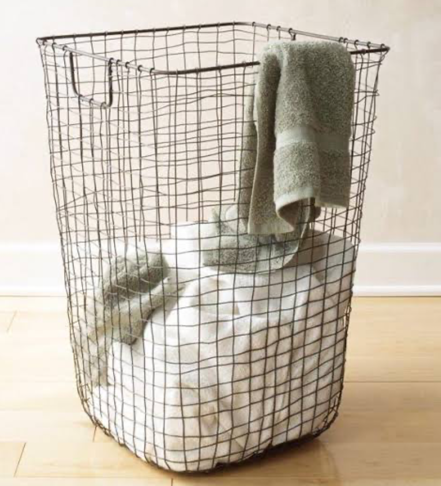 Wire laundry basket filled with towels and folded blanket.