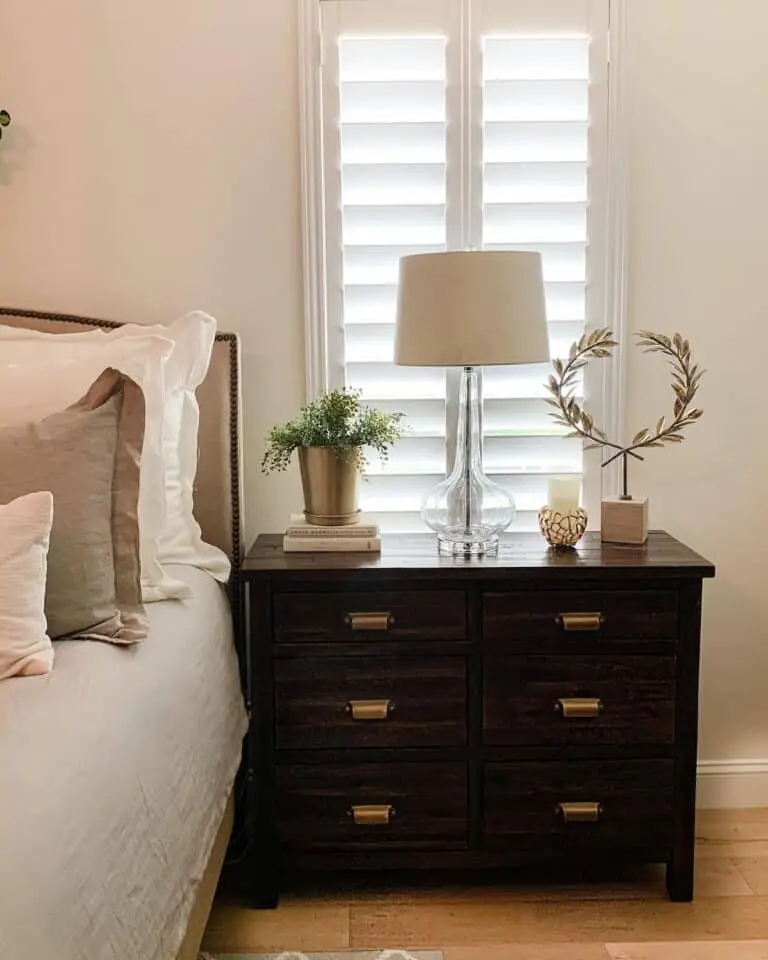 Cozy bedroom with dark wood nightstand and soft lighting.