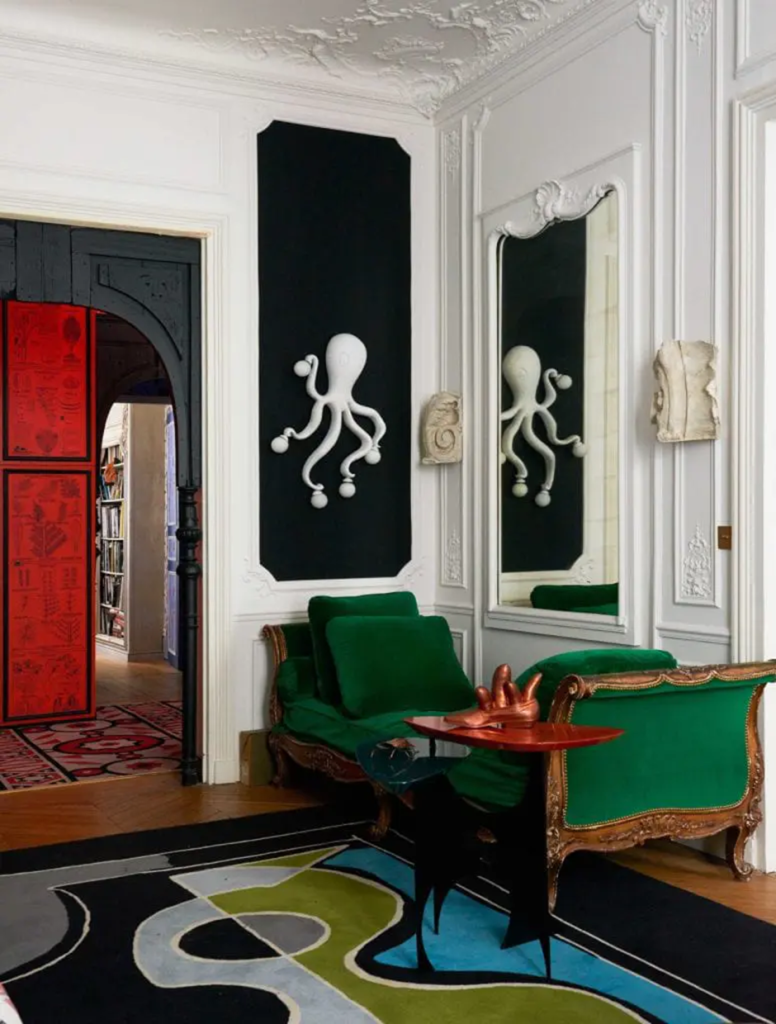 Eclectic salon with green velvet chaise lounge and octopus wall sculpture.
