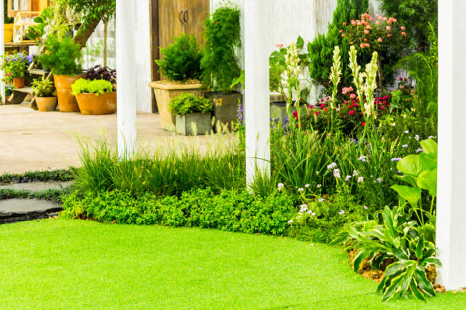 Lush lawn border with ornamental grasses, potted plants, and cottage-style flowers