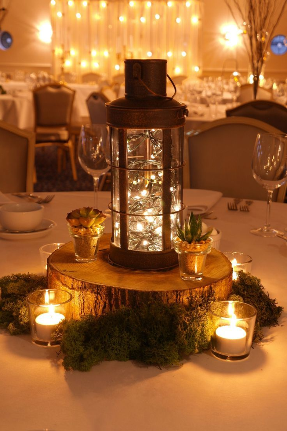 Rustic lantern centerpiece with fairy lights and candles.