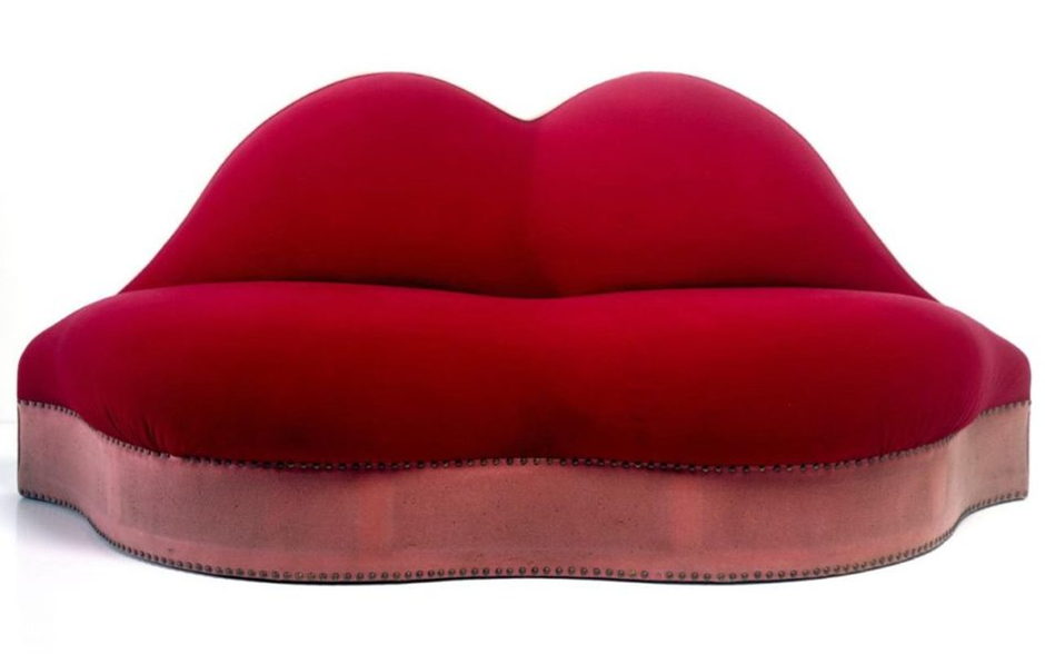 Iconic red lips sofa inspired by surrealist art, studio background.