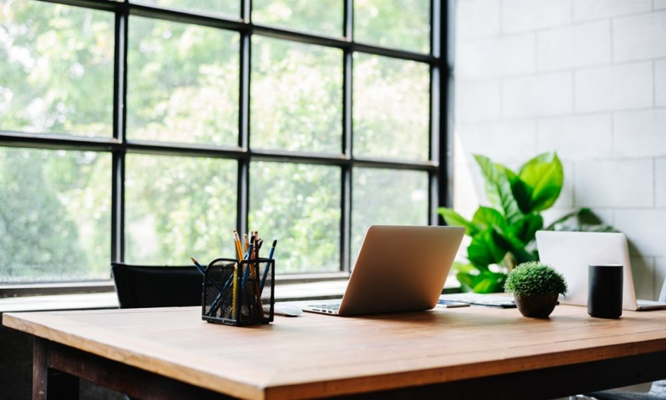 Bright home office with large industrial windows and dual-laptop workspace