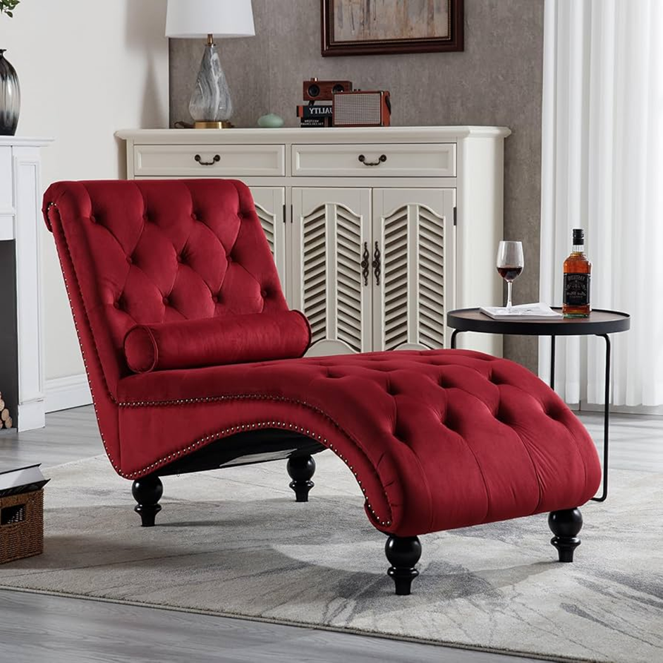 Curved tufted red velvet chaise with a side table, wine glass, and bottle for a cozy, luxe vibe.