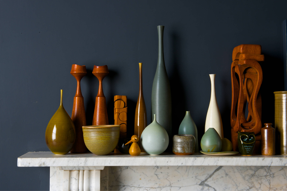 Mid-century pottery collection on marble mantel against dark wall