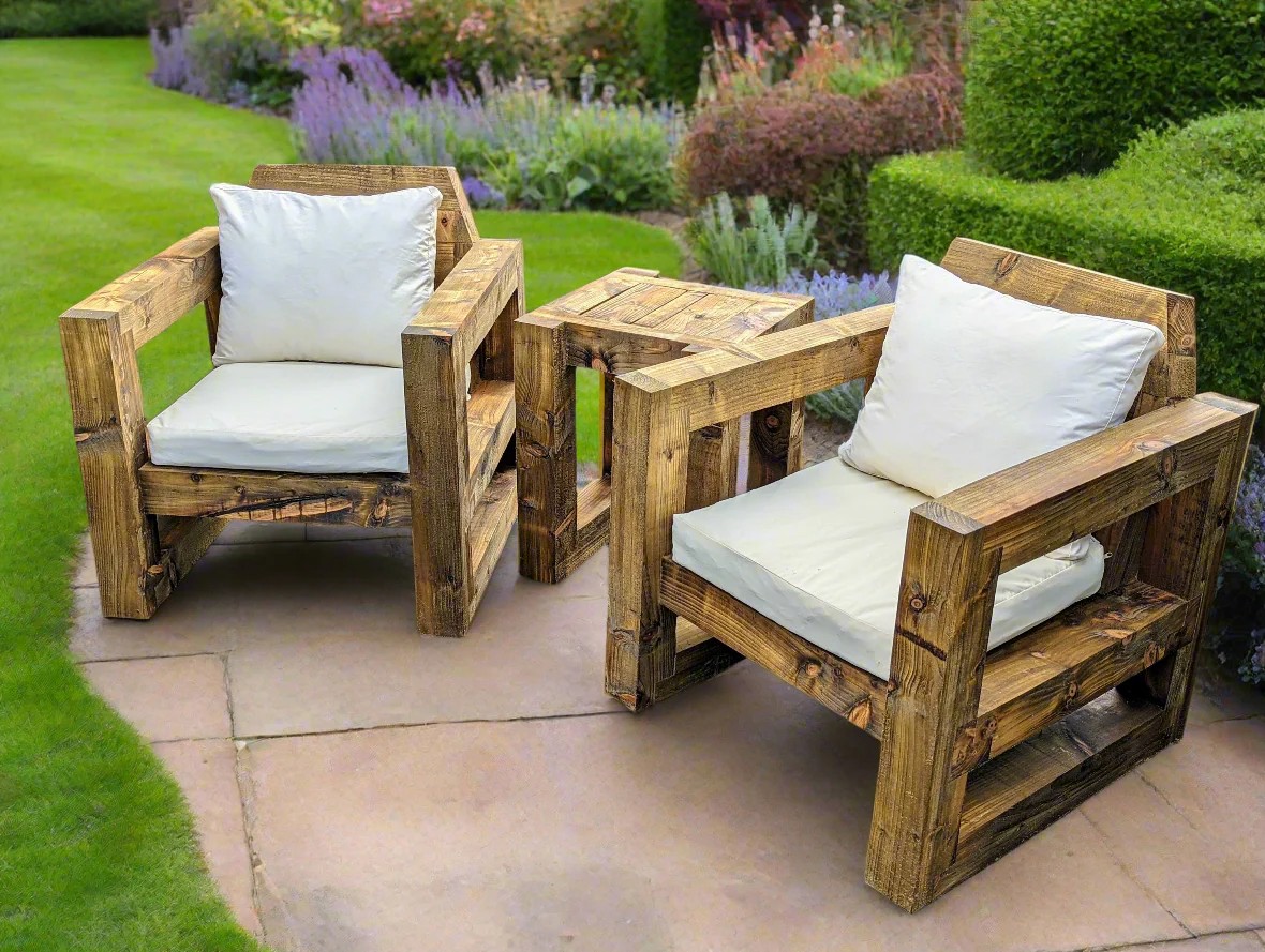 Two rustic outdoor chairs set on a small paved area in front of a garden.