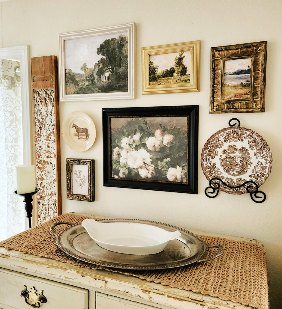 Vintage gallery wall with landscapes, florals, and transferware plates.