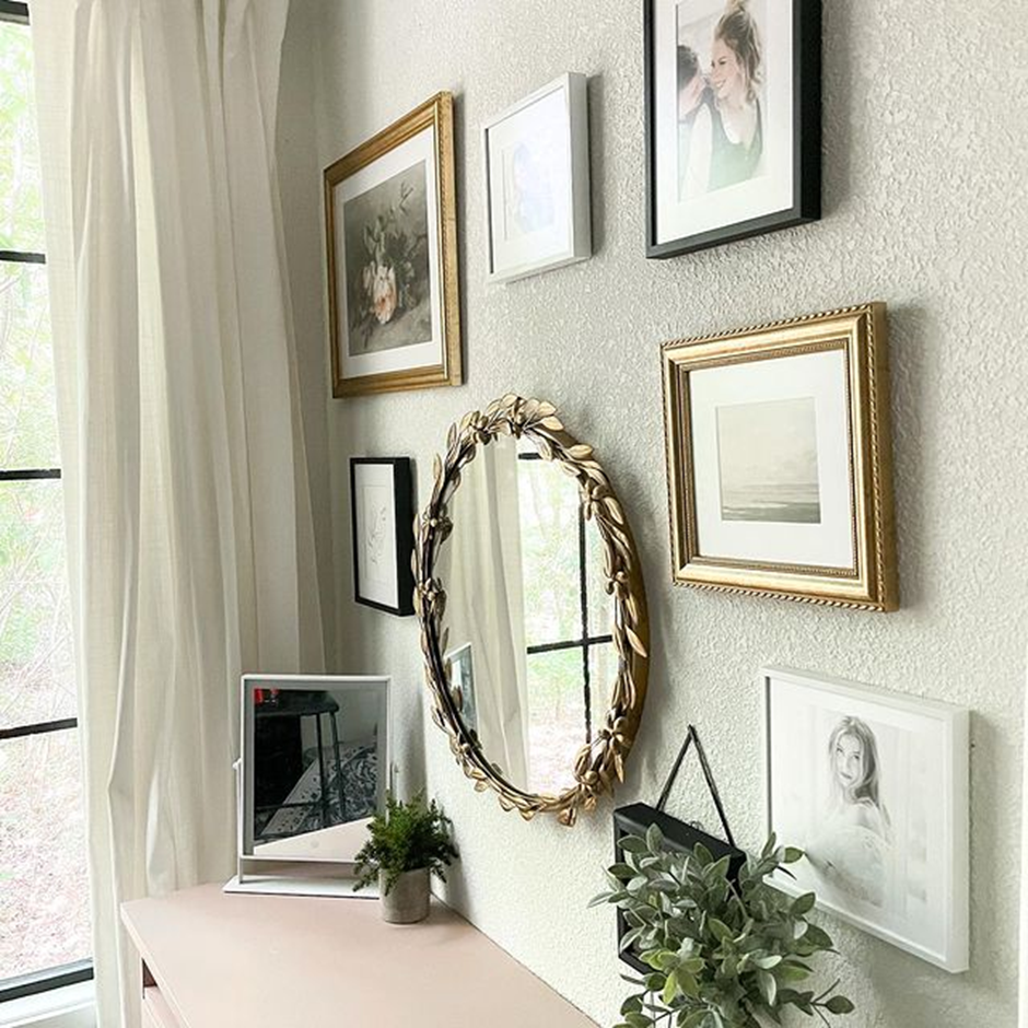 Elegant gallery wall with gold mirror and framed photos.
