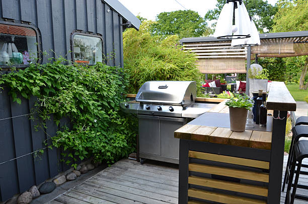 Outdoor grill on a patio next to herb garden growing along side the wall.