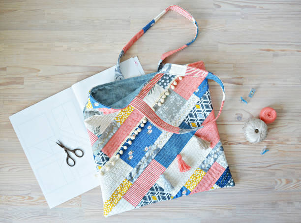 Quilted boho tote bag, scissors, clips and thread on wooden tabletop.