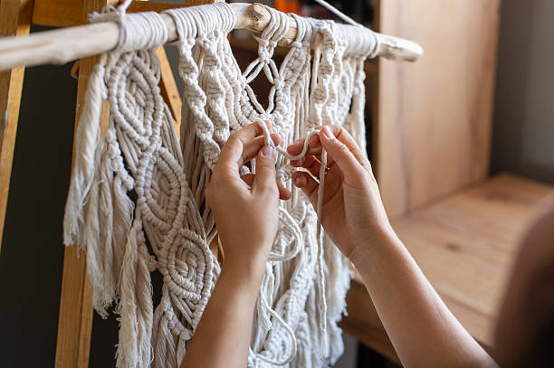 Close-up view of skilled hands intricately weaving a beautiful macrame wall decoration