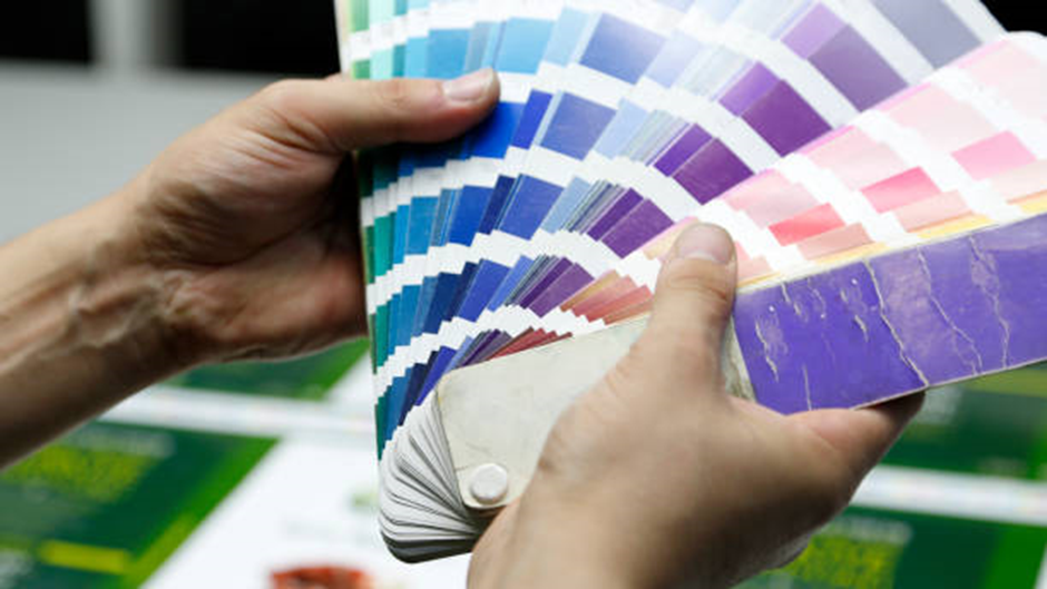 hands holding a fan of colorful paint swatches for color selection