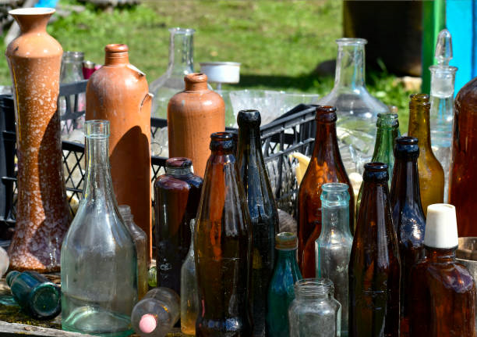 collection of old glass and ceramic bottles displayed on outdoor table