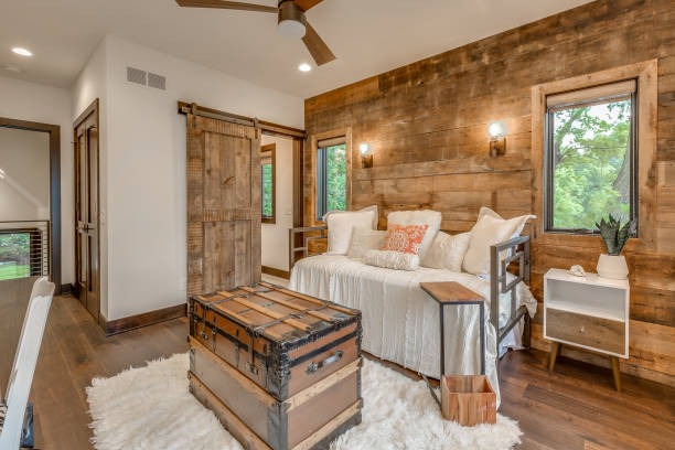 Rustic farmhouse bedroom with wooden accent wall, barn door, and vintage trunk furniture
