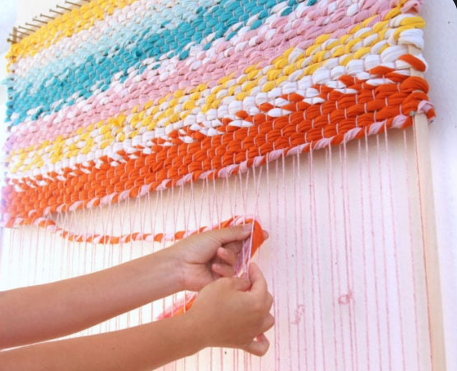 hand weaving colorful yarn wall hanging rug on loom with modern textile pattern