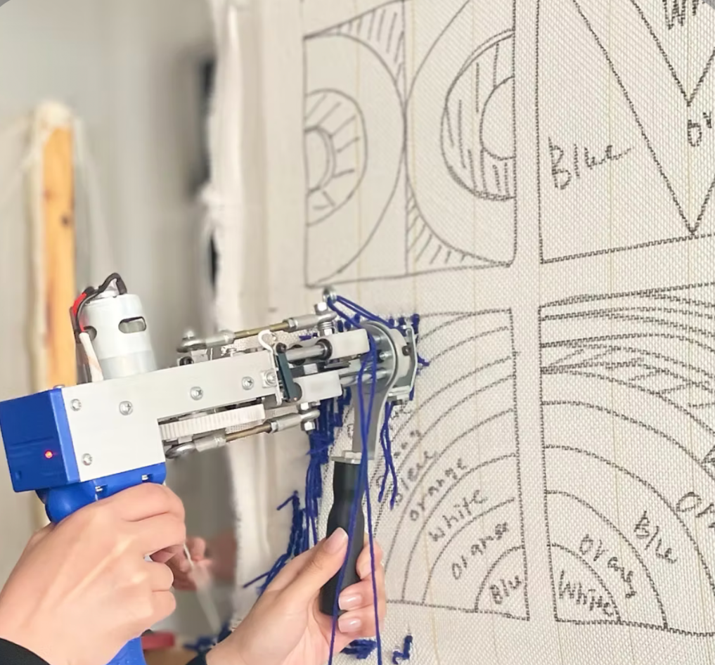 close up of rug tufting machine creating custom handmade rug design on fabric backing